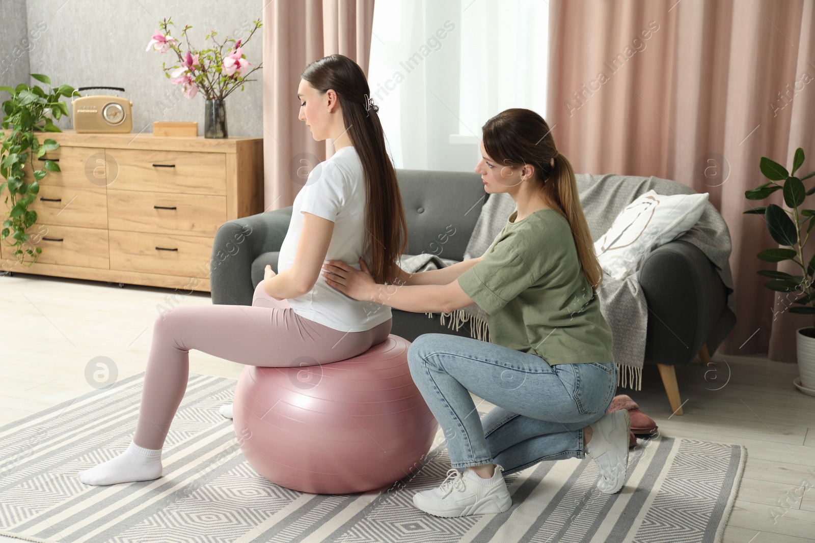 Photo of Doula massaging pregnant woman at home. Preparation for child birth