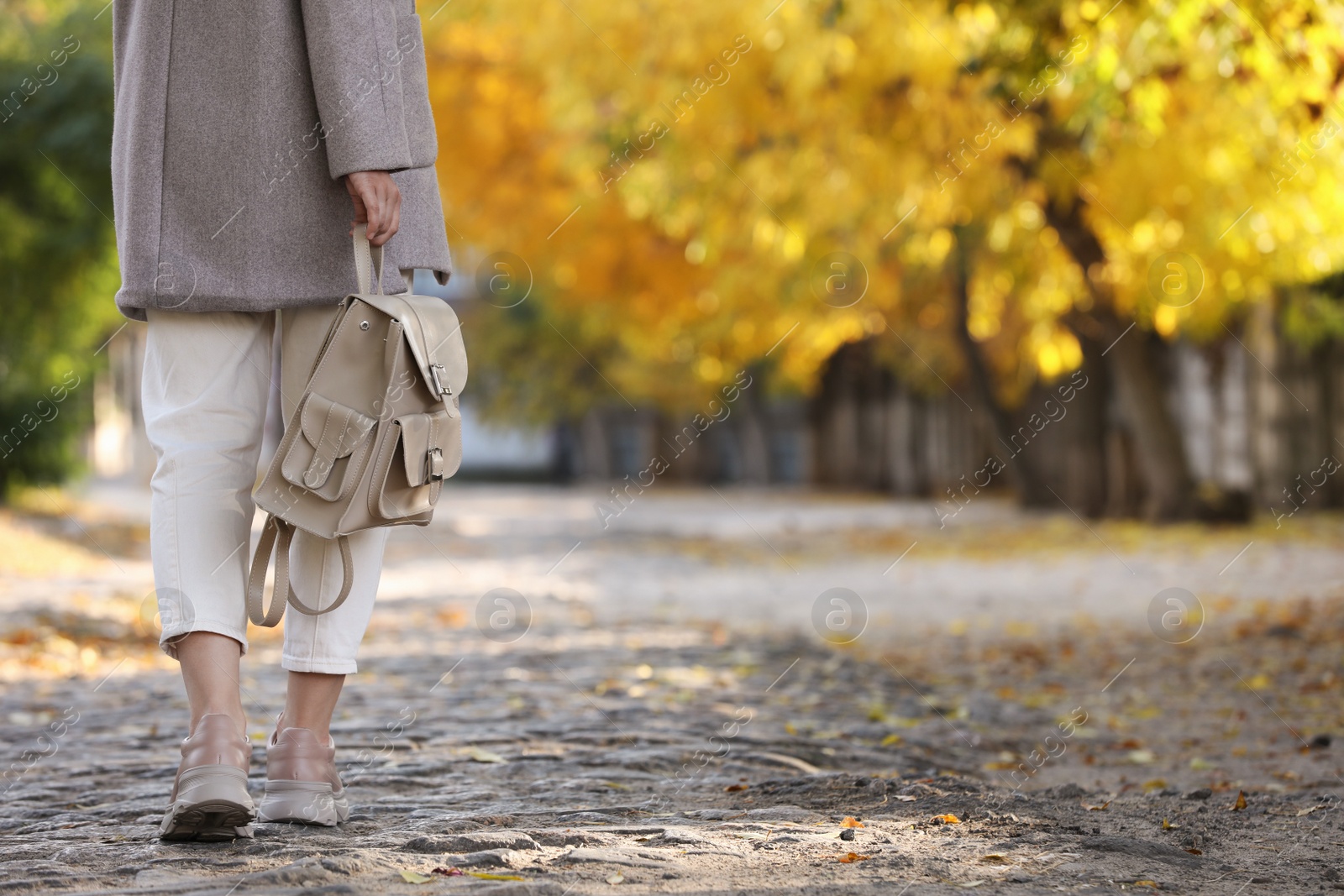 Photo of Young woman with stylish beige backpack on city street, closeup. Space for text