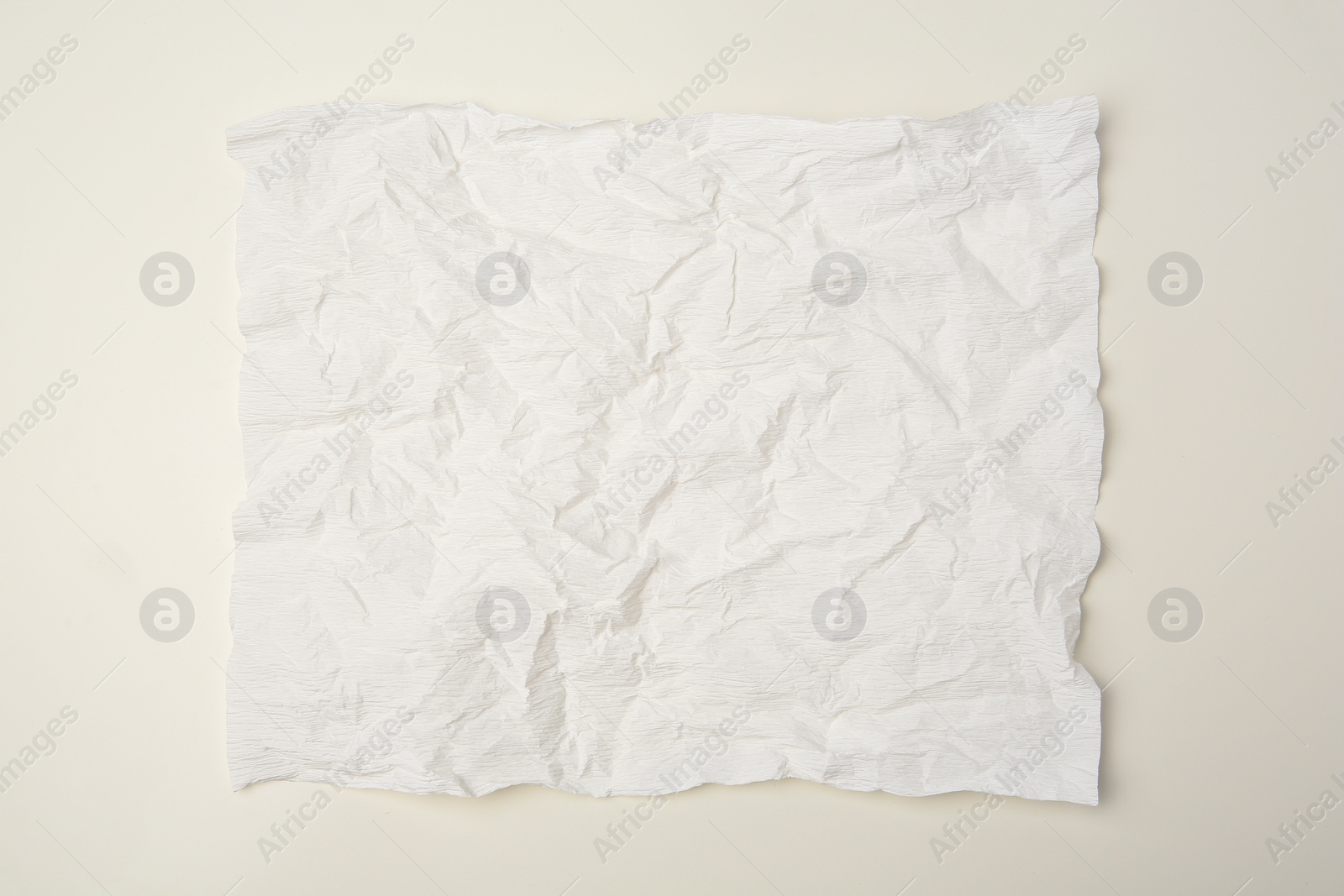 Photo of Sheet of crumpled paper on beige background, top view