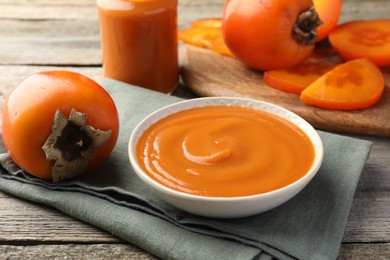 Photo of Delicious persimmon jam and fresh fruits on wooden table