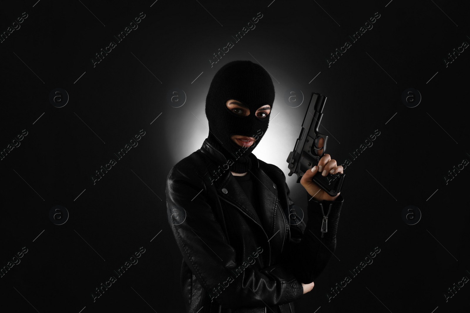 Photo of Woman wearing knitted balaclava with gun on black background