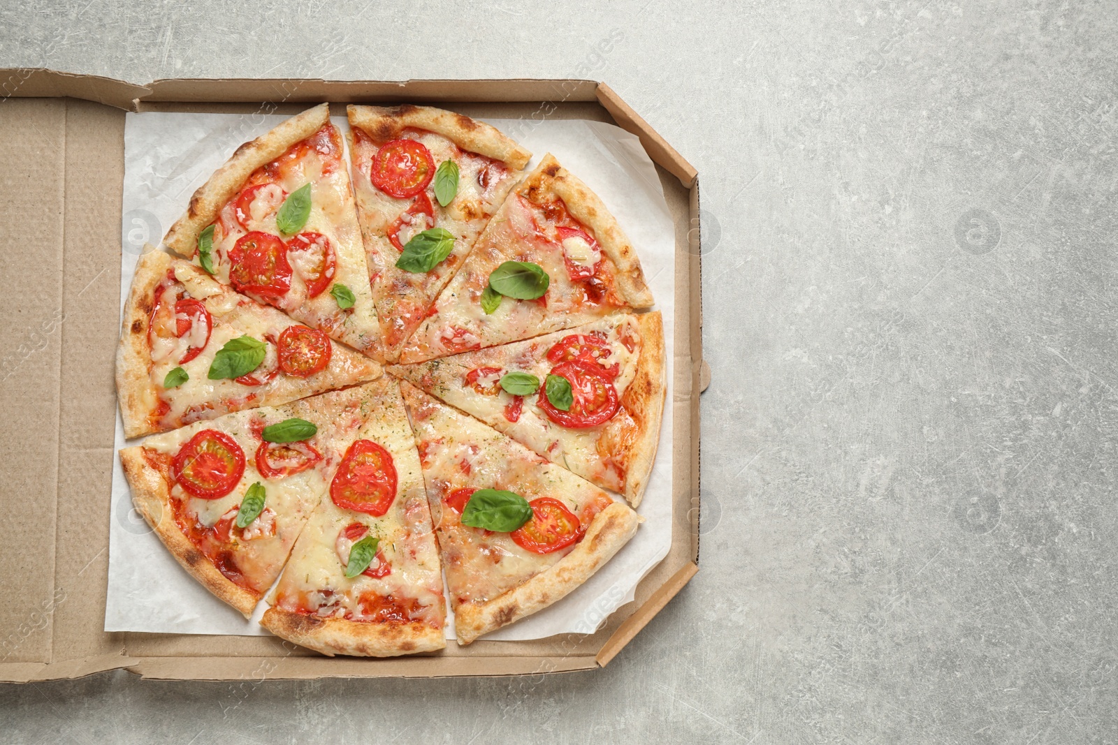 Photo of Delicious pizza Margherita in box on light grey table, top view. Space for text