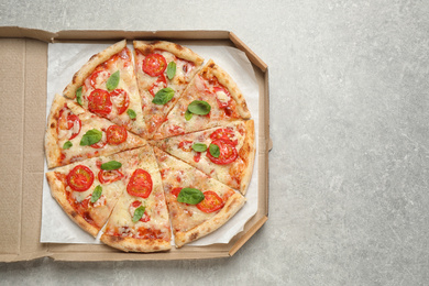Photo of Delicious pizza Margherita in box on light grey table, top view. Space for text