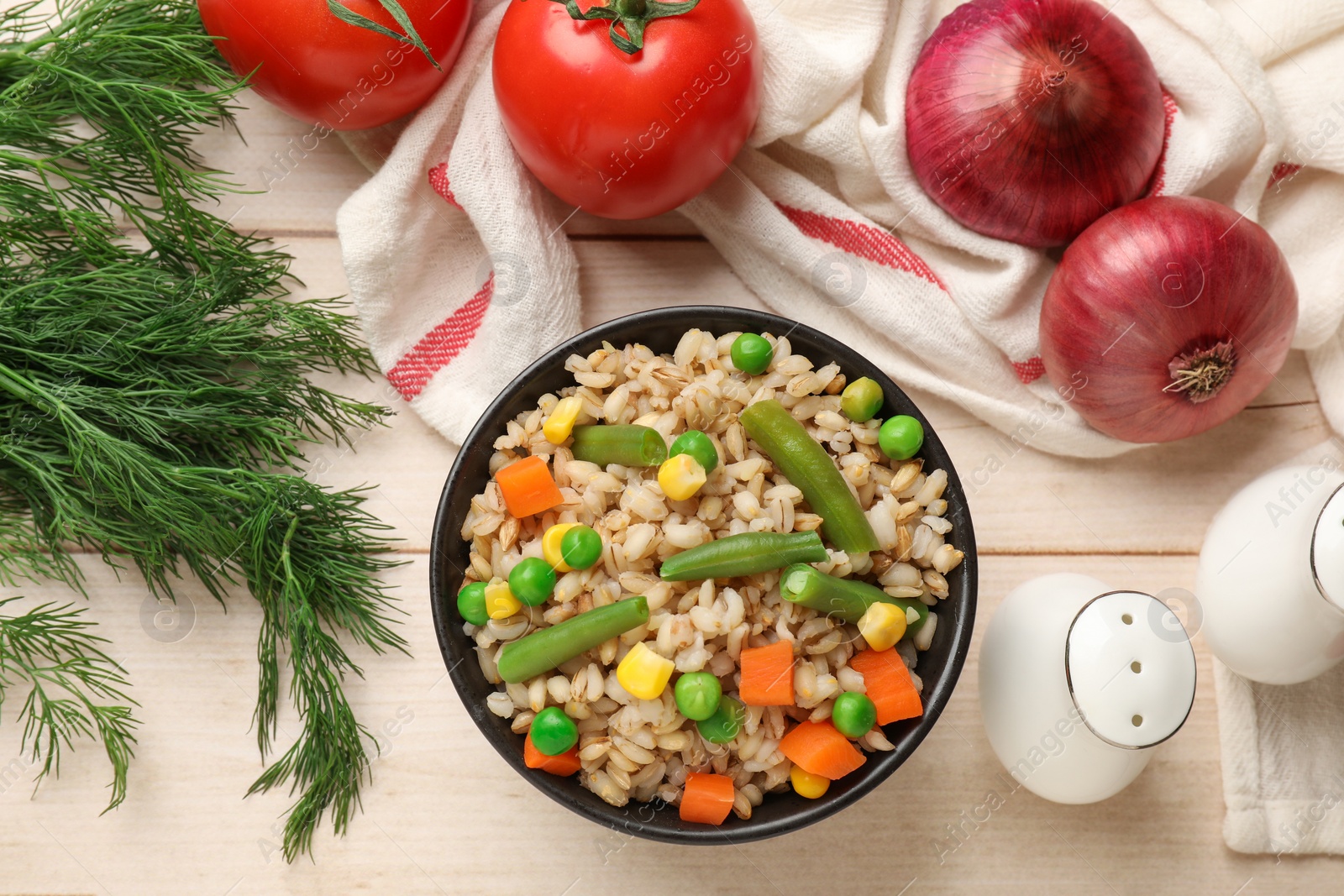 Photo of Delicious pearl barley with vegetables and other products on wooden table, flat lay