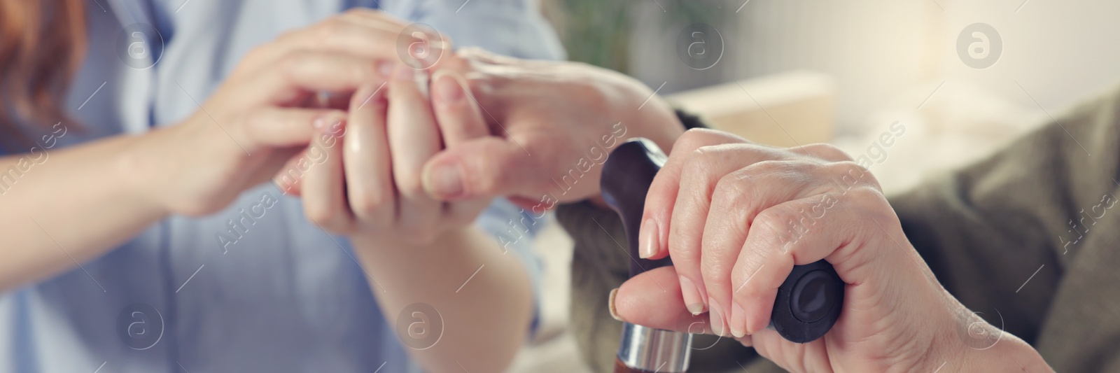 Image of Caregiver and elderly woman with walking cane at home, closeup. Banner design