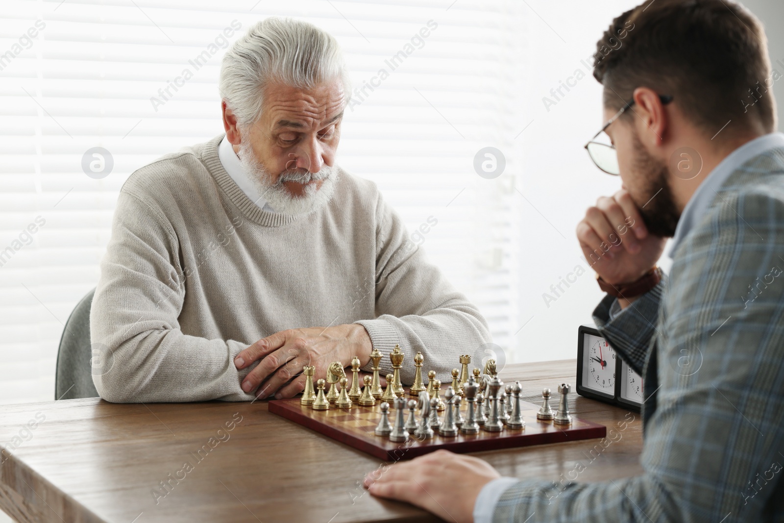 Photo of Men playing chess during tournament at table indoors