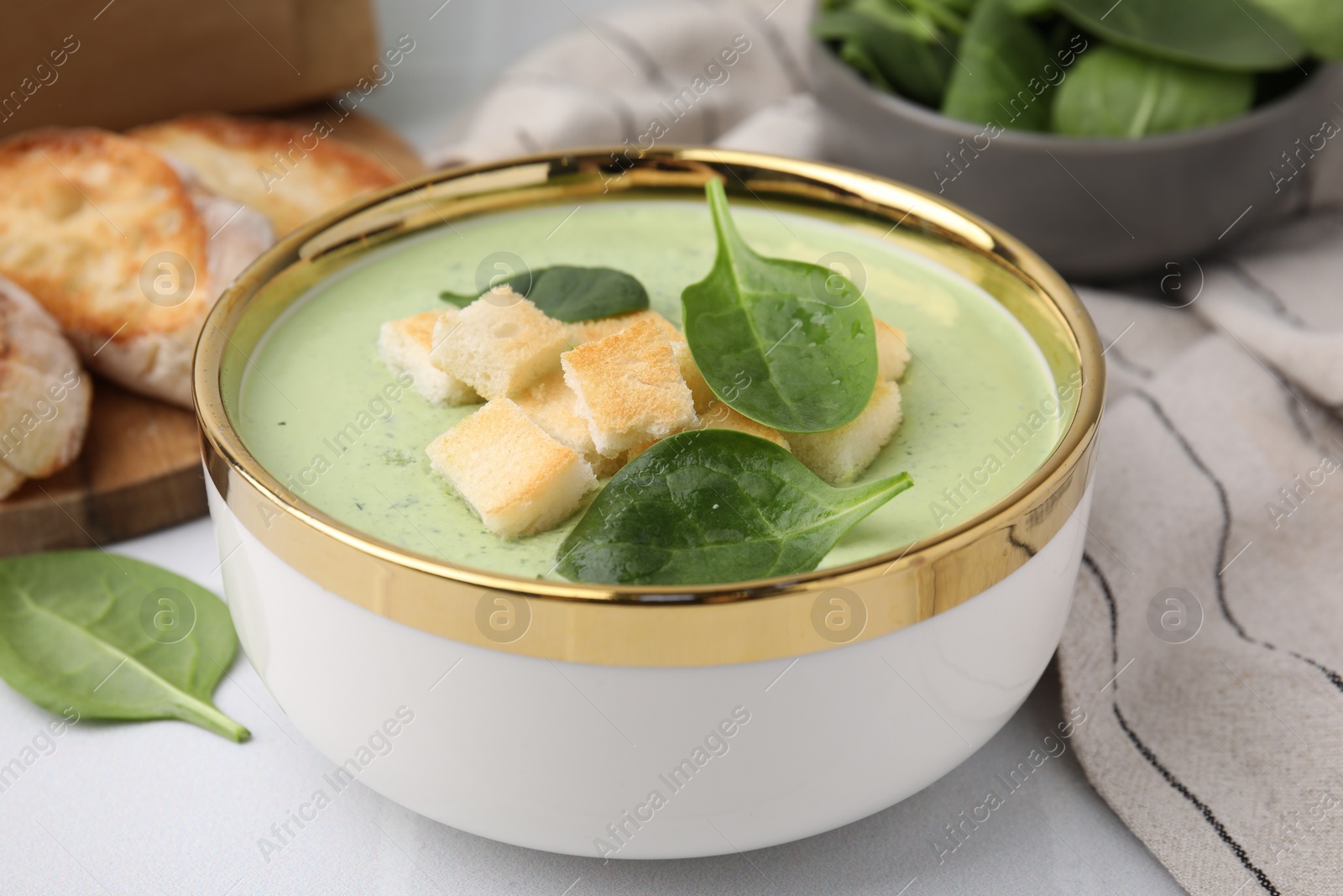 Photo of Delicious spinach cream soup with croutons in bowl on white table