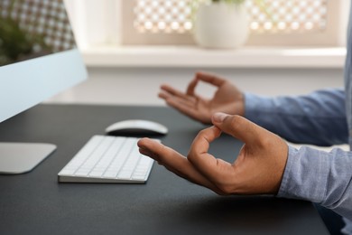 Businessman meditating at workplace, closeup. Zen concept