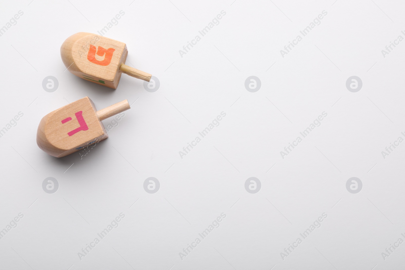 Photo of Wooden dreidels on white background, flat lay with space for text. Traditional Hanukkah game