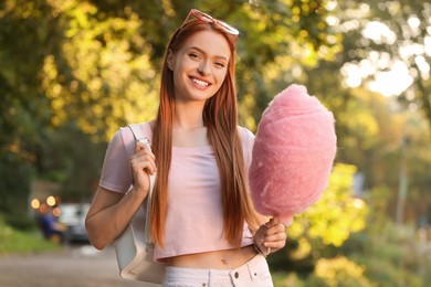 Portrait of smiling woman with cotton candy outdoors on sunny day
