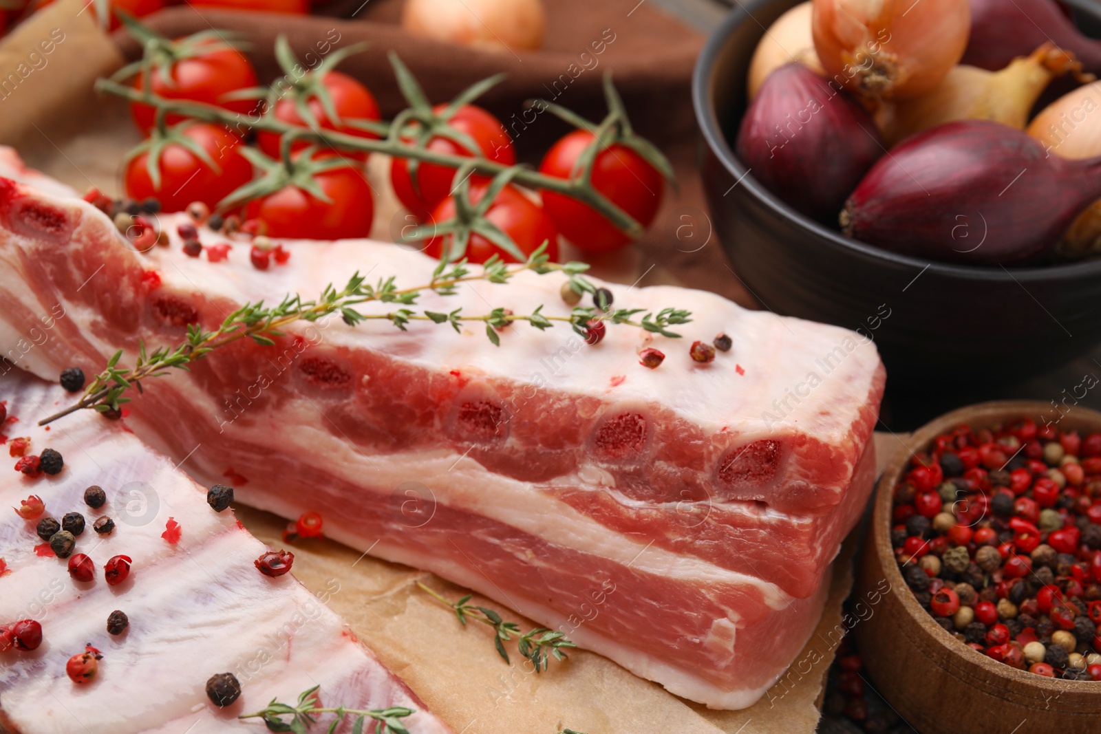 Photo of Raw pork ribs with thyme and peppercorns on table, closeup