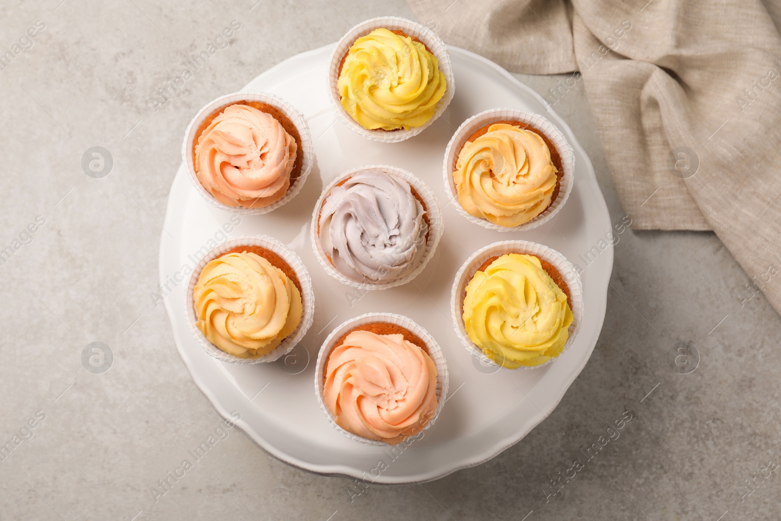 Photo of Stand with tasty cupcakes on light table, flat lay