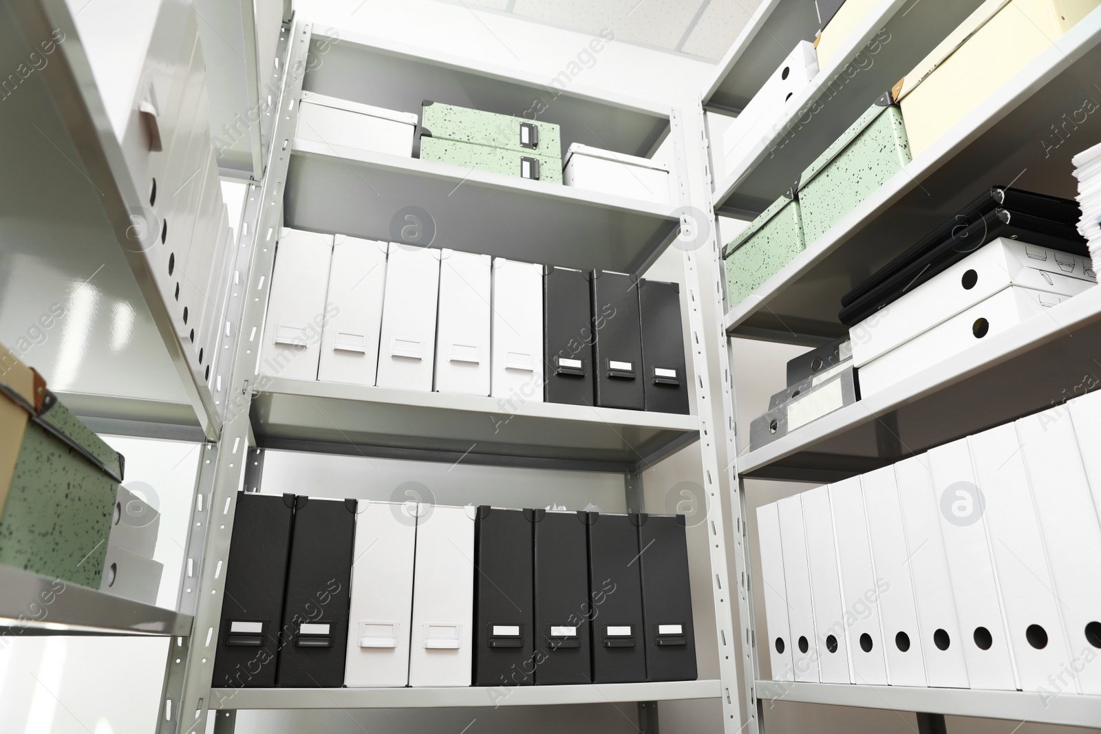 Photo of Folders and boxes with documents on shelves in archive, low angle view