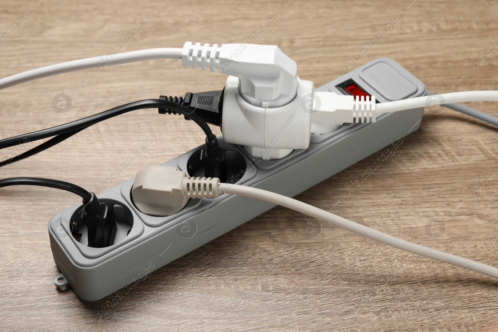 Photo of Power strip with extension cord on wooden floor. Electrician's equipment