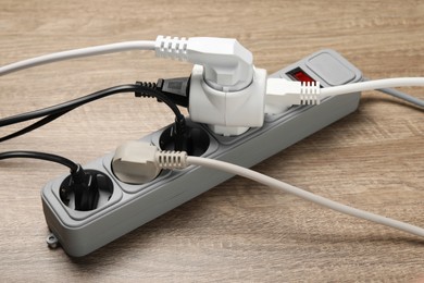 Photo of Power strip with extension cord on wooden floor. Electrician's equipment