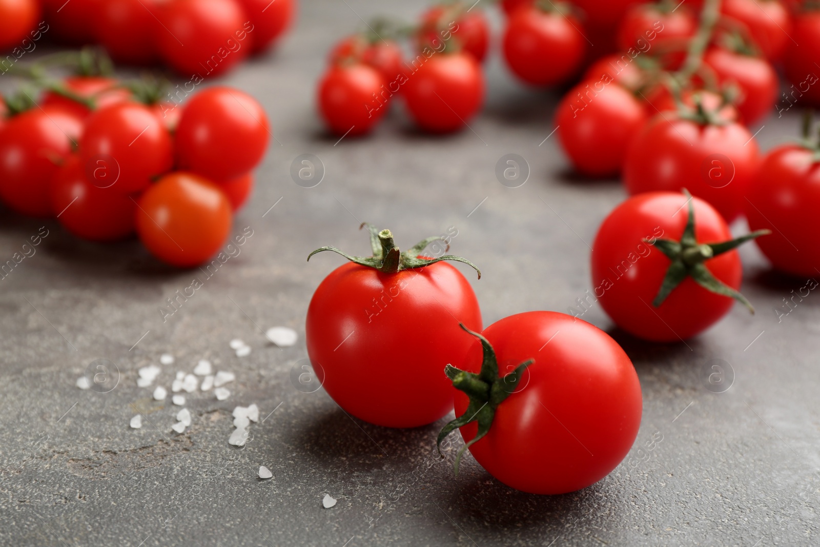 Photo of Fresh ripe cherry tomatoes and salt on grey table