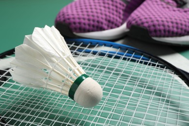 Feather badminton shuttlecock, racket and sneakers on court, closeup