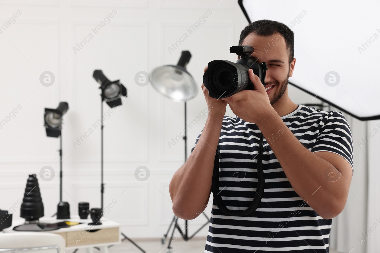 Photo of Young professional photographer taking picture in modern photo studio, space for text