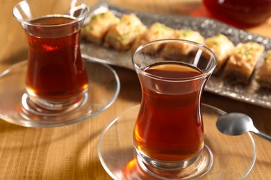 Photo of Traditional Turkish tea in glasses on wooden table, closeup