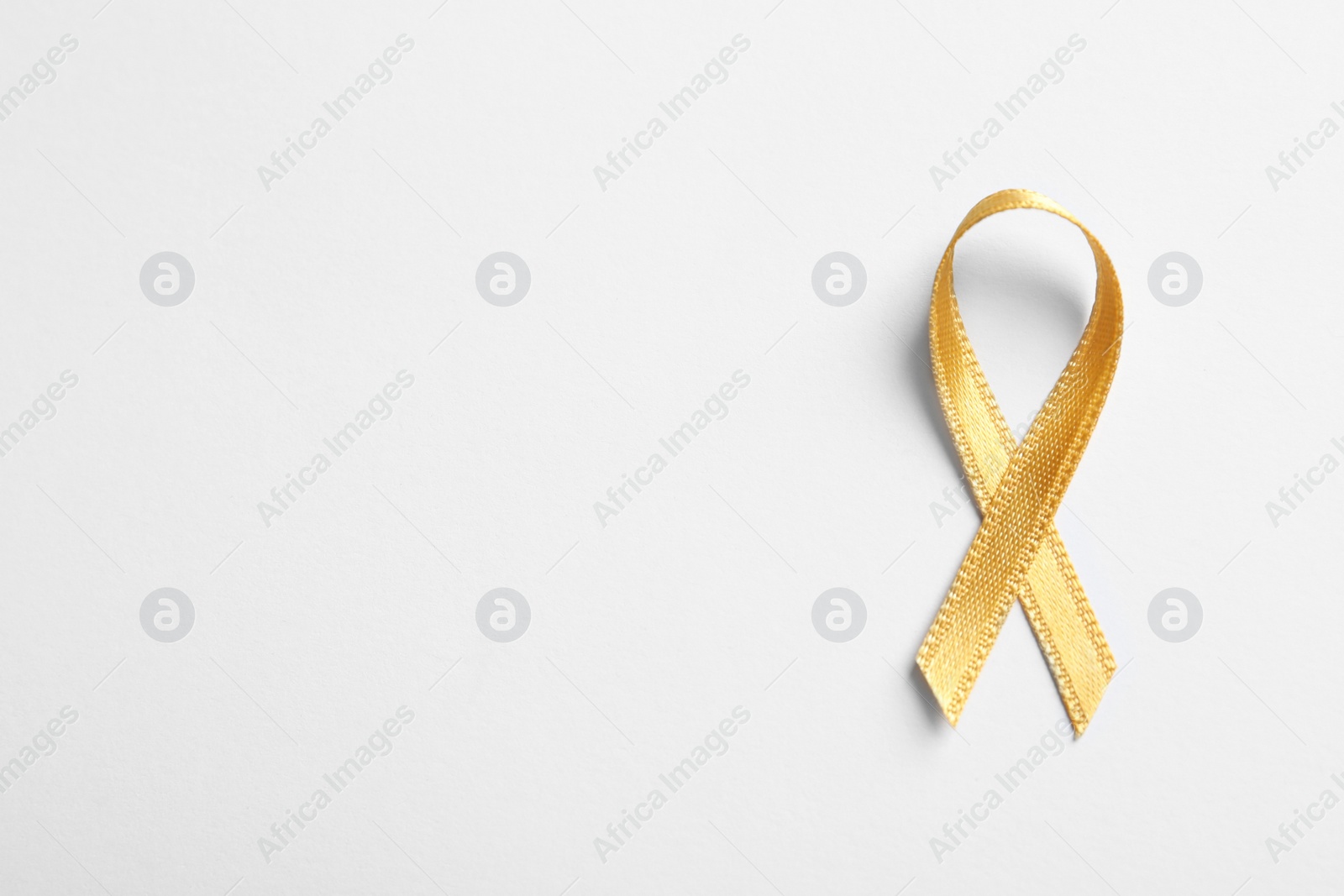 Photo of Yellow ribbon on white background, top view. Cancer awareness