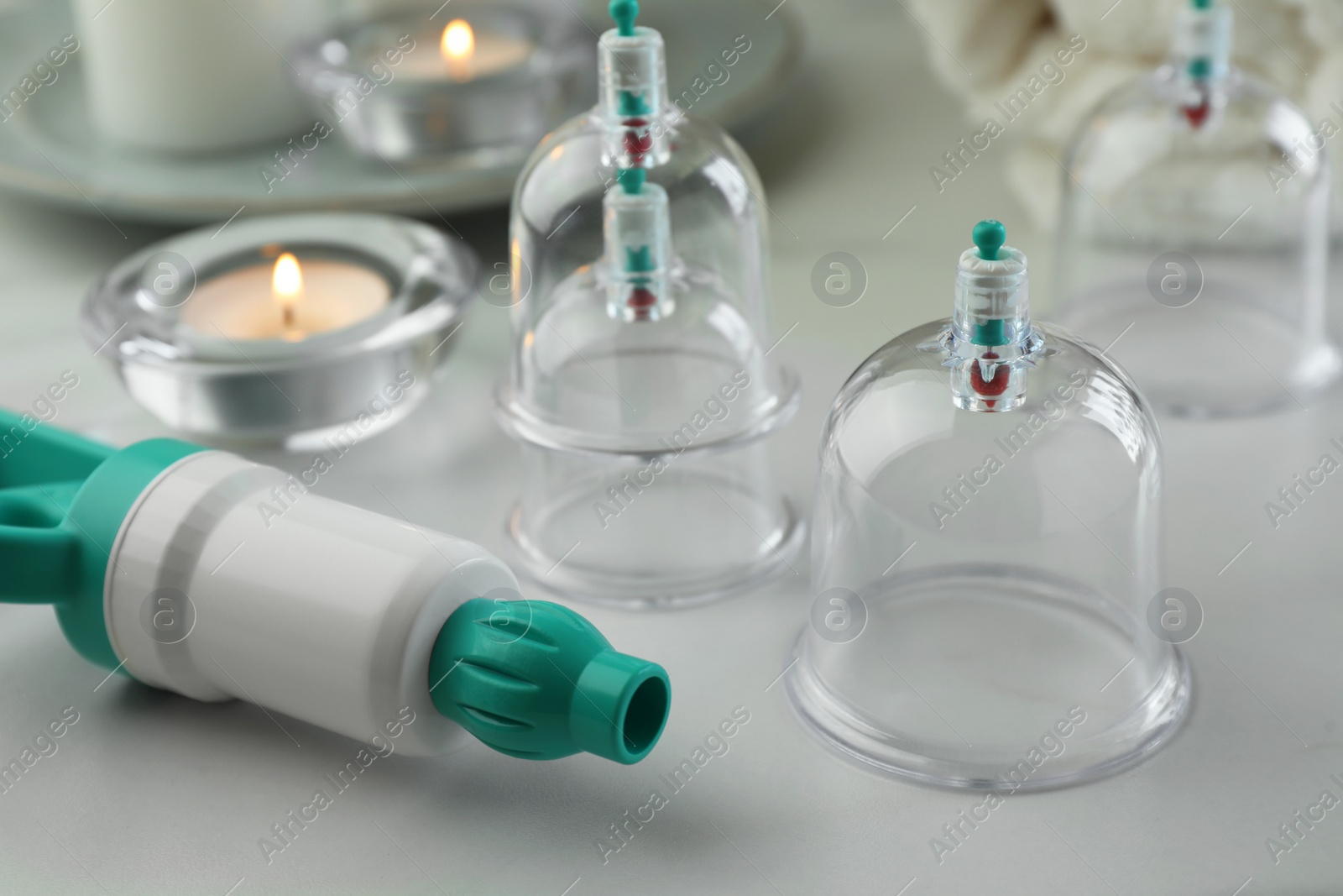 Photo of Plastic cups and hand pump on white table, closeup. Cupping therapy