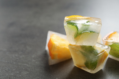 Photo of Ice cubes with orange and mint on grey table, closeup. Space for text