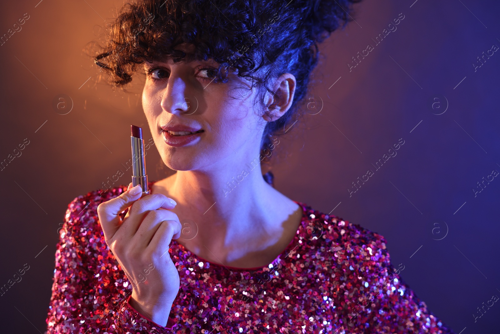 Photo of Beautiful young woman with lipstick posing on color background in neon lights