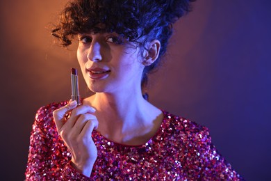 Beautiful young woman with lipstick posing on color background in neon lights