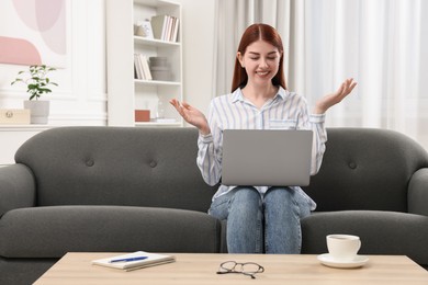 Happy woman with laptop having video chat in room