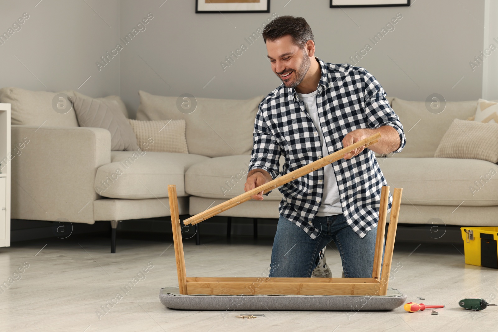 Photo of Man assembling shoe storage bench on floor at home