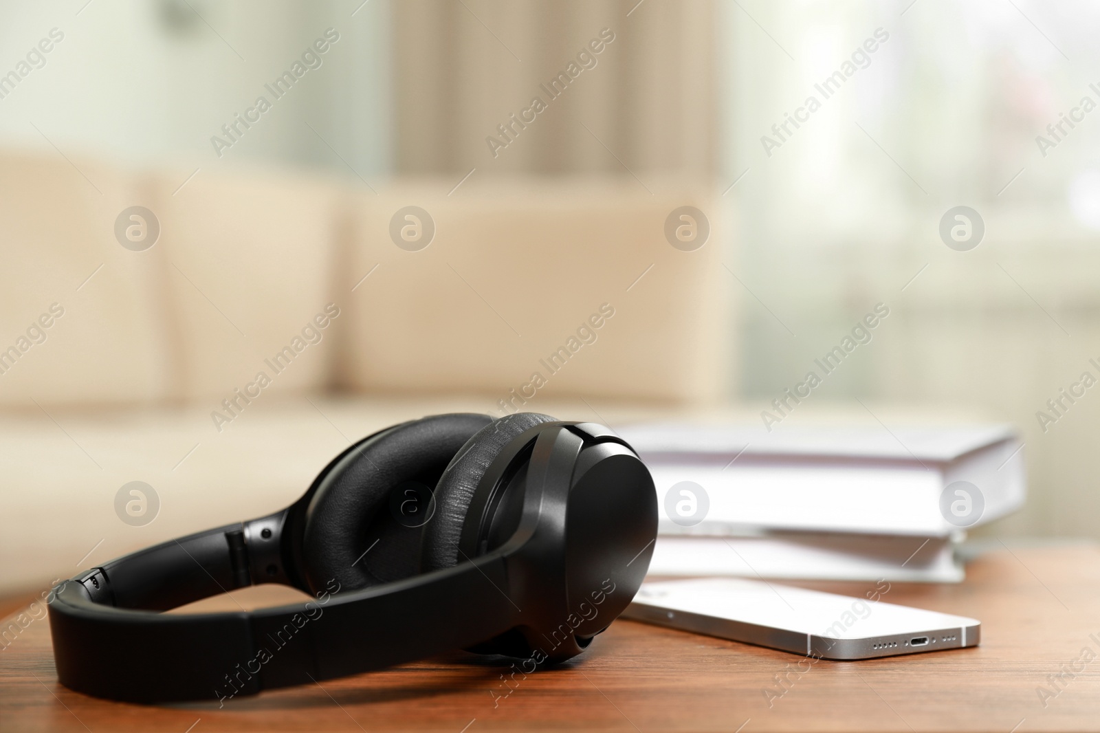 Photo of Modern wireless headphones and smartphone on wooden table indoors