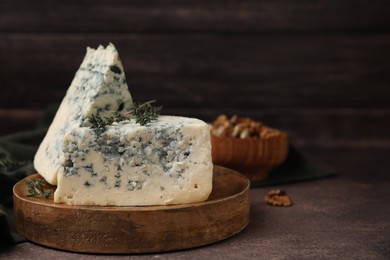 Photo of Tasty blue cheese with thyme on brown table. Space for text