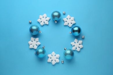 Bright festive wreath made of Christmas balls and decorative snowflakes on light blue background, top view. Space for text