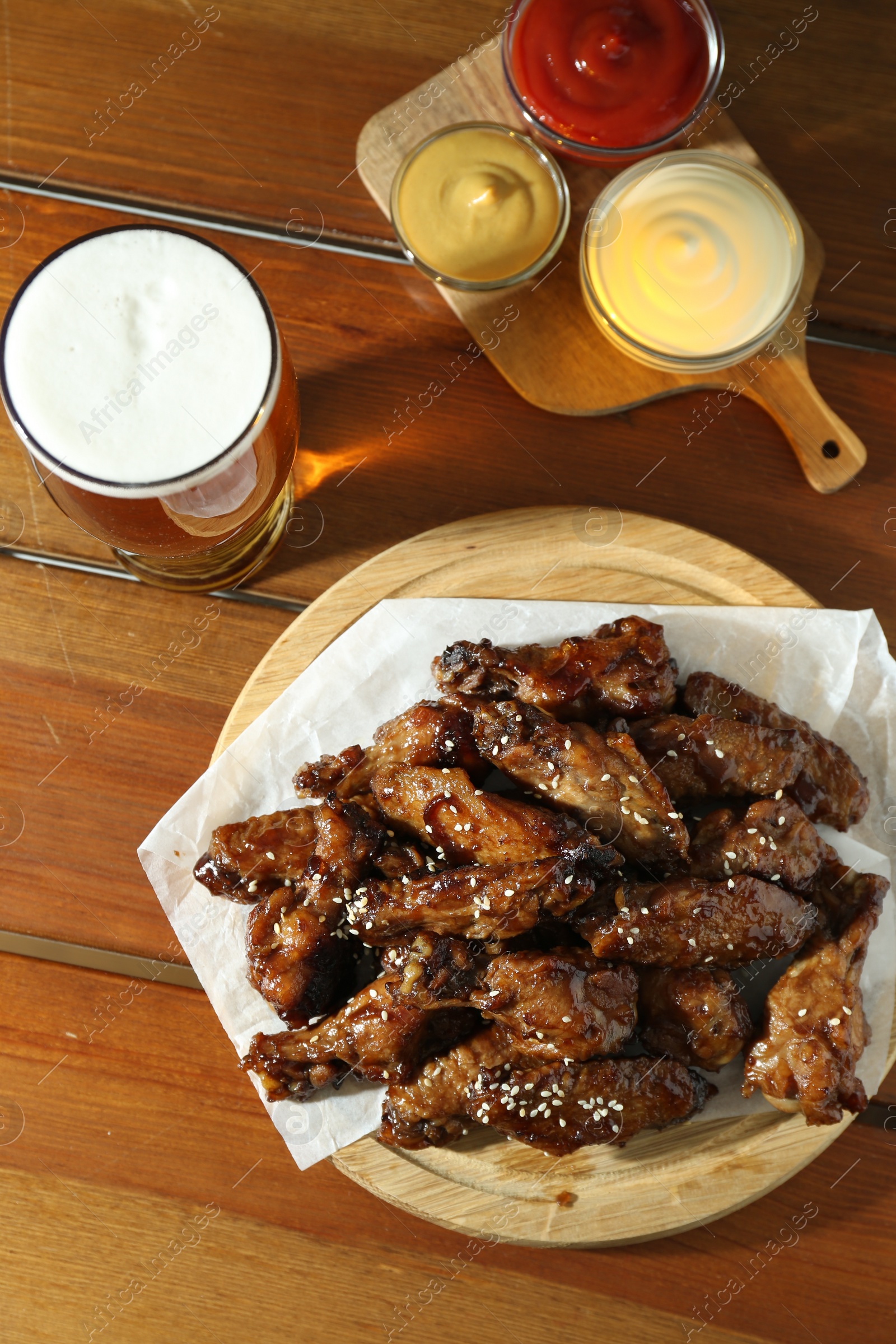 Photo of Tasty roasted chicken wings served with beer on wooden table