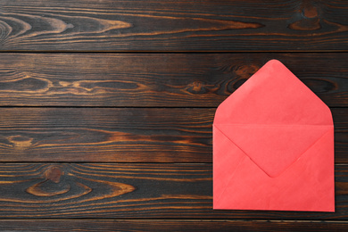 Photo of Red paper envelope on wooden background, top view. Space for text