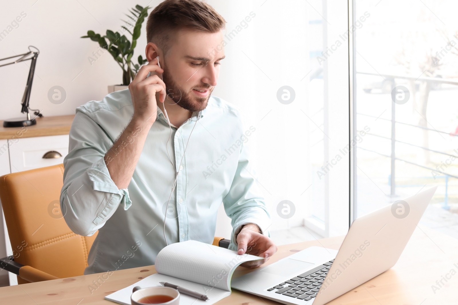 Photo of Young man working with laptop at desk. Home office