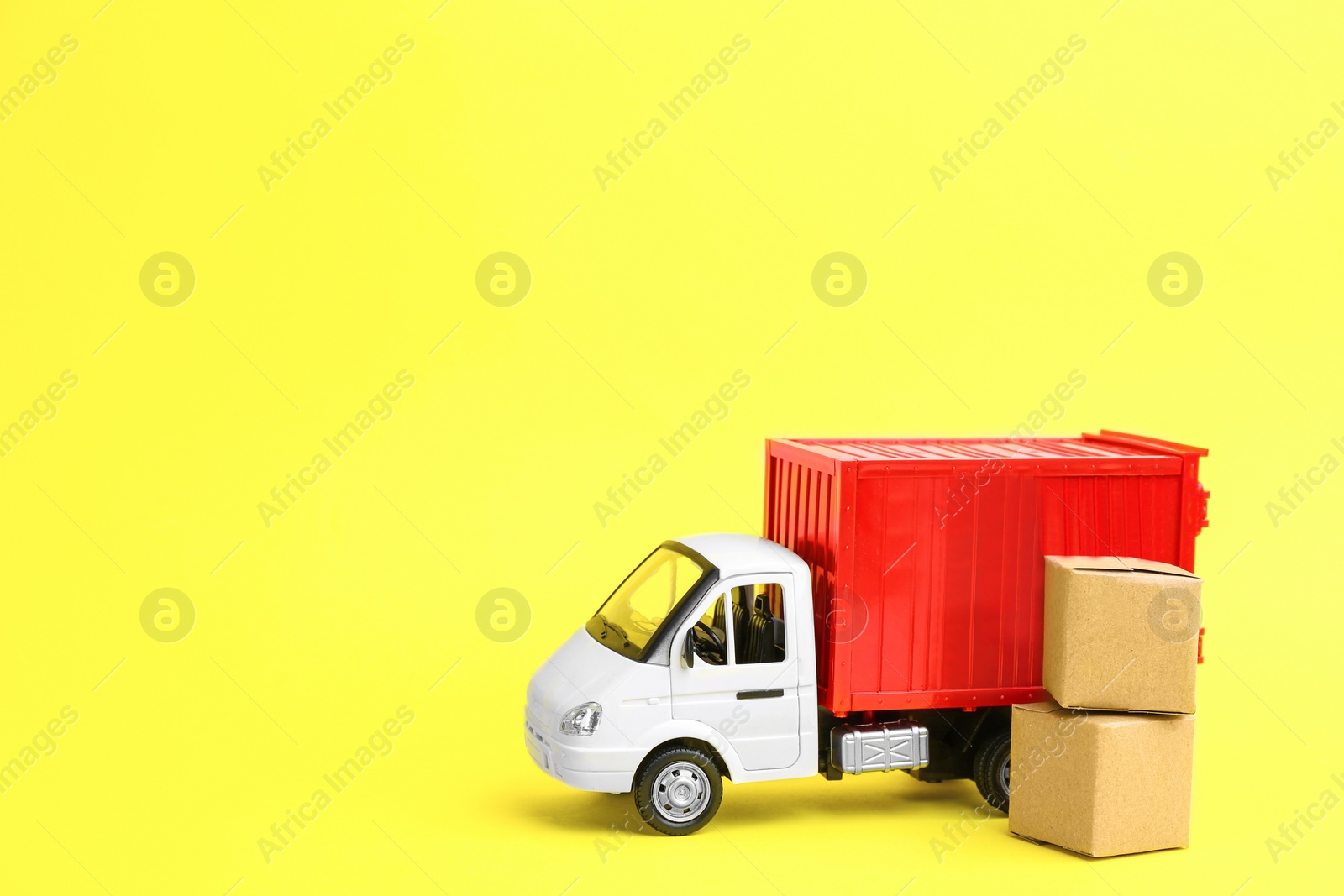 Photo of Truck model and carton boxes on yellow background, space for text. Courier service