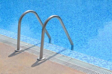 Photo of Outdoor swimming pool with ladder and handrails on sunny day