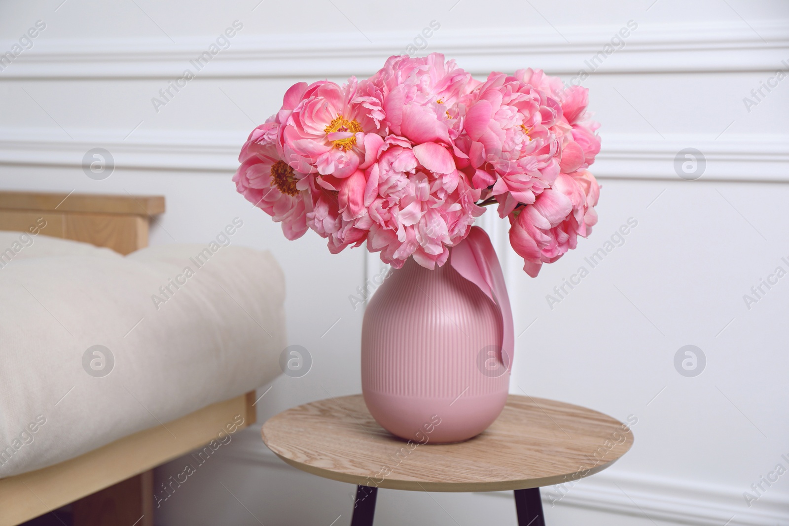 Photo of Beautiful bouquet of pink peonies in vase on wooden table indoors