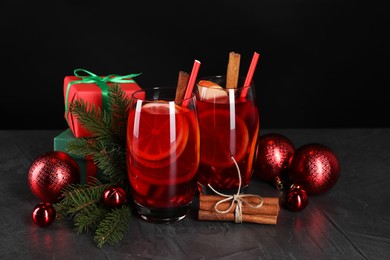 Photo of Delicious Sangria drink in glasses and Christmas decorations on dark textured table, closeup