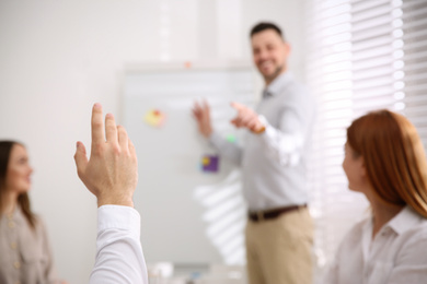 Photo of Young man raising hand to ask question at business training in conference room, closeup