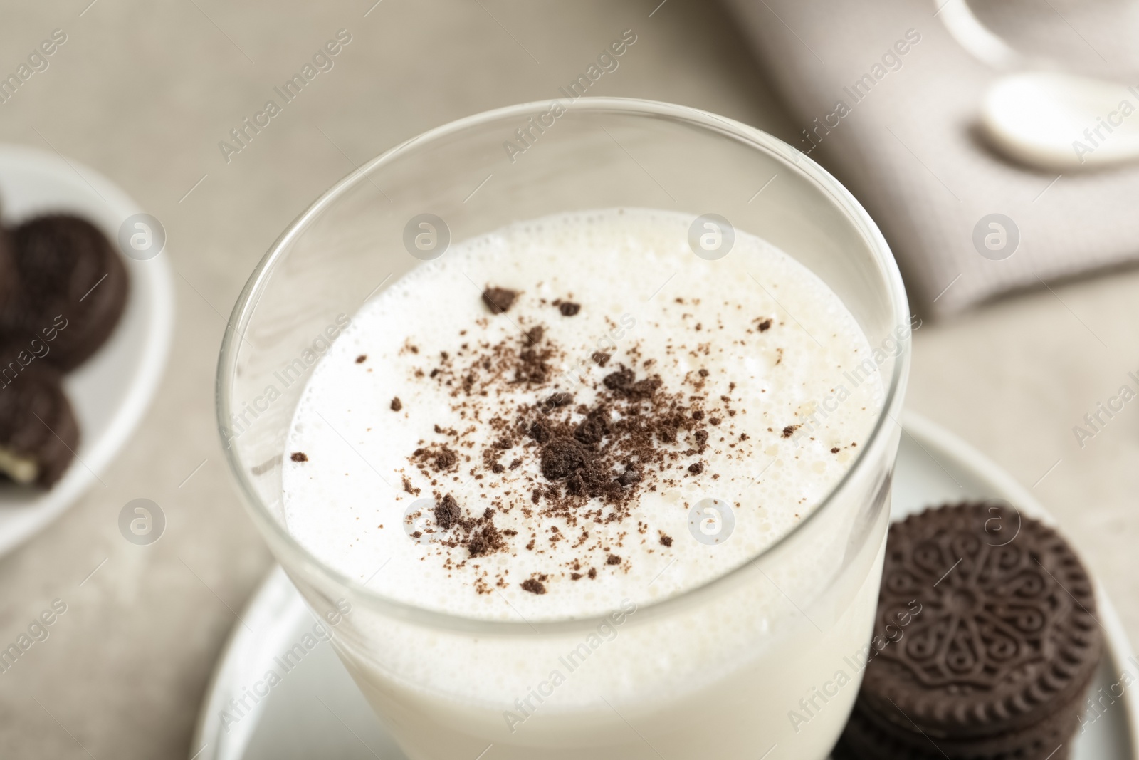 Photo of Glass of milk with chocolate cookie crumbs on table, closeup