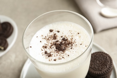 Glass of milk with chocolate cookie crumbs on table, closeup