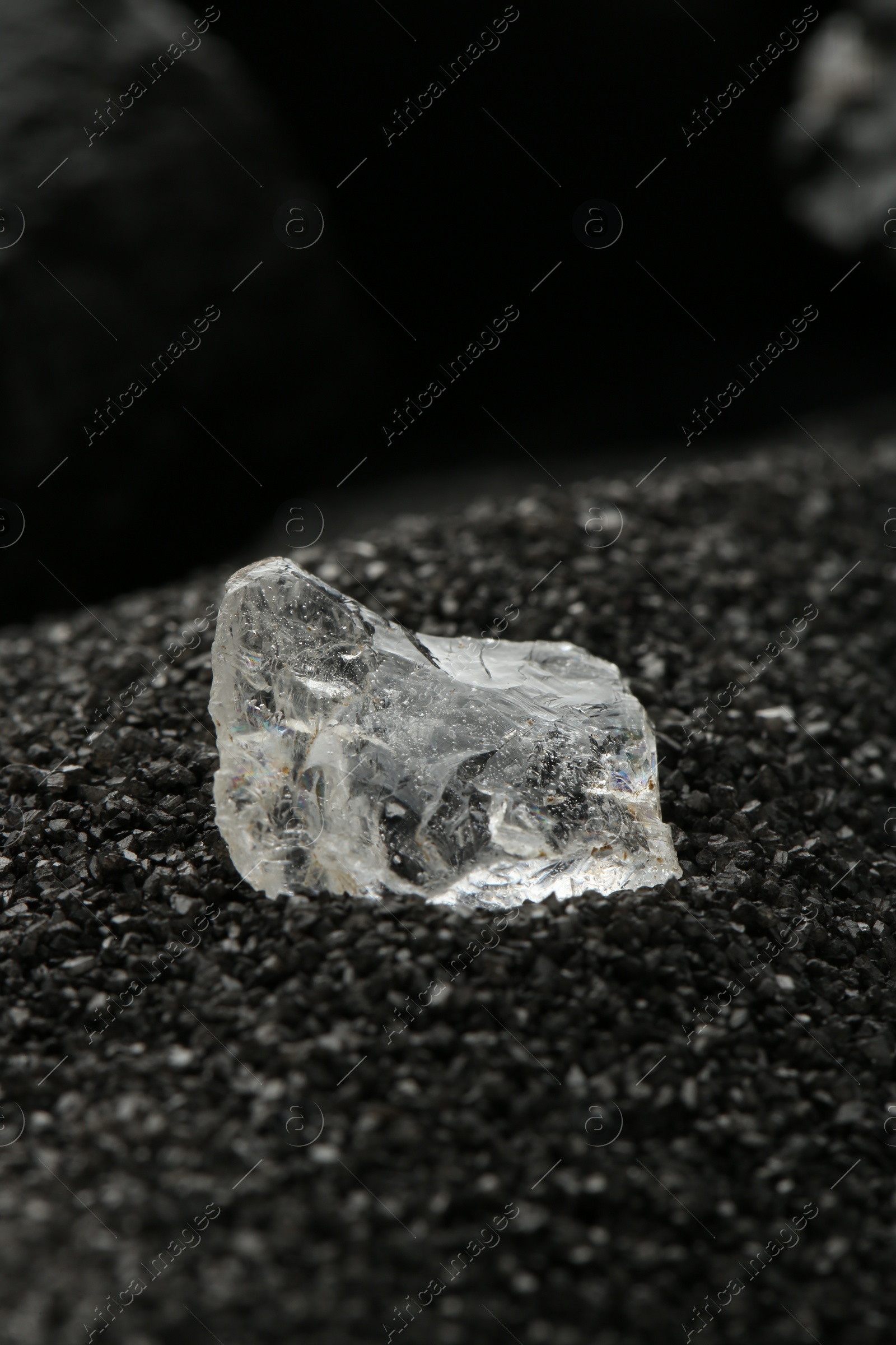 Photo of Shiny rough diamond on decorative black sand