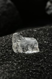 Photo of Shiny rough diamond on decorative black sand