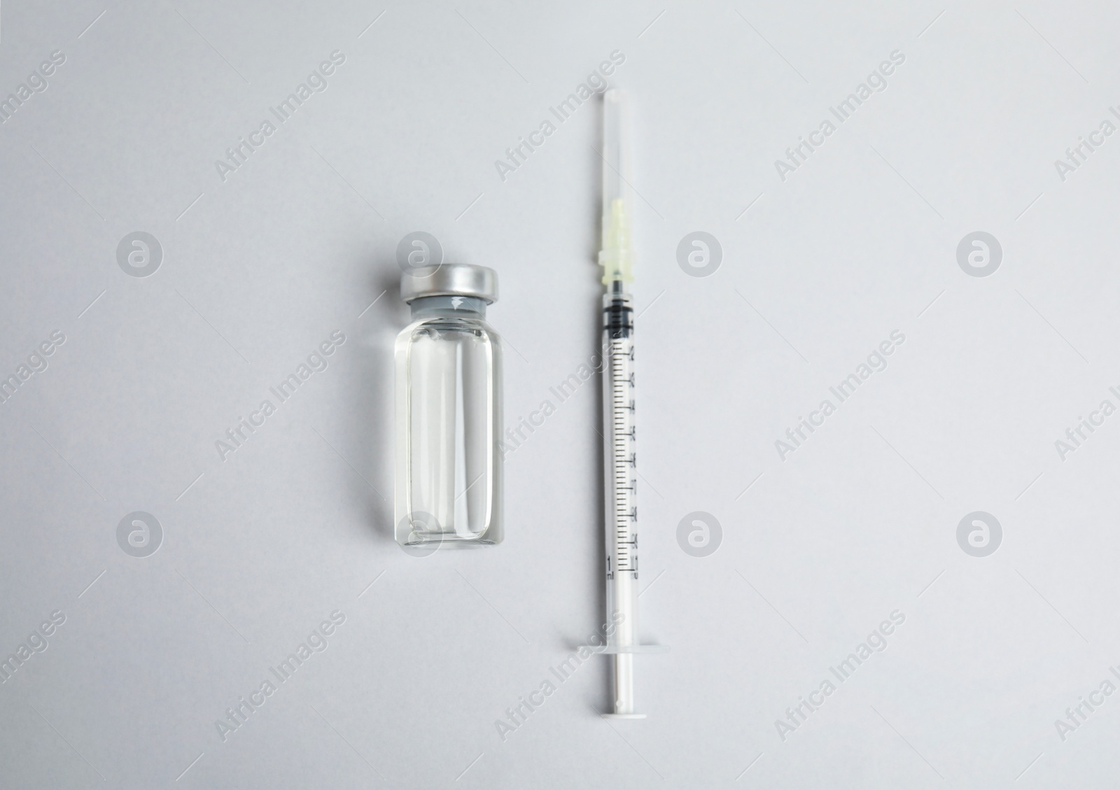 Photo of Vial and syringe on light background, flat lay. Vaccination and immunization