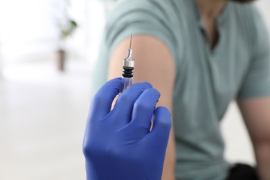 Doctor giving injection to man in hospital, closeup. Immunization concept