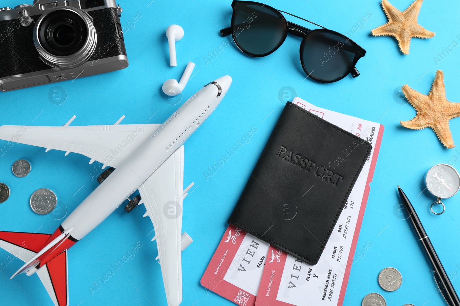 Photo of Flat lay composition with toy airplane and travel items on light blue background