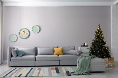 Photo of Light living room interior with Christmas tree and large sofa