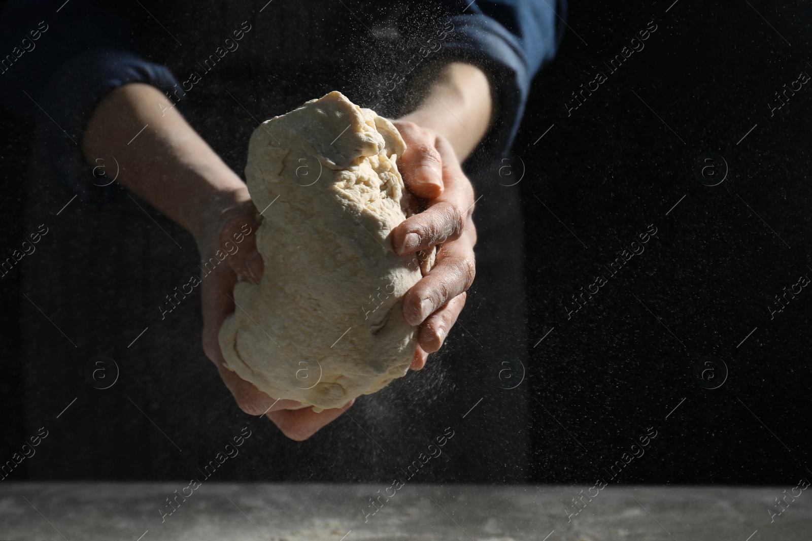 Photo of Making bread. Woman kneading dough at table on dark background, closeup. Space for text